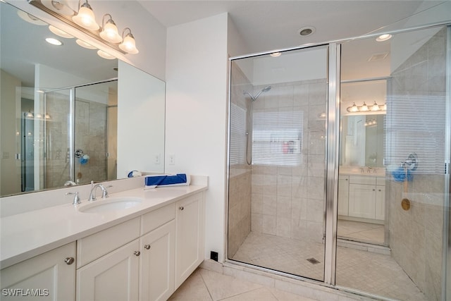 bathroom with a shower with door, vanity, and tile patterned flooring