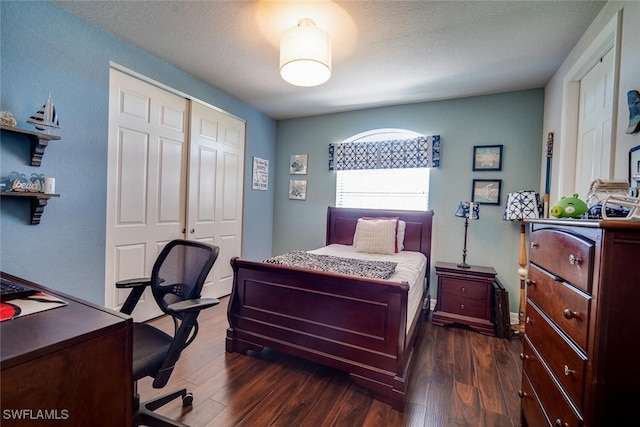 bedroom with a closet, a textured ceiling, and dark hardwood / wood-style floors