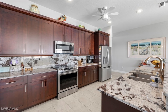 kitchen featuring decorative backsplash, light stone countertops, stainless steel appliances, and sink