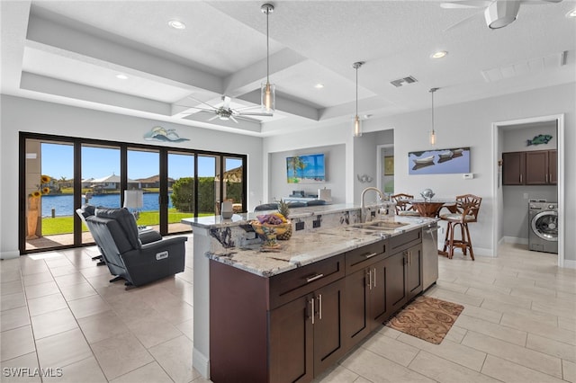 kitchen featuring sink, decorative light fixtures, a water view, and washer / clothes dryer