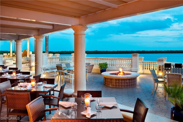 patio terrace at dusk with an outdoor living space with a fire pit and a water view