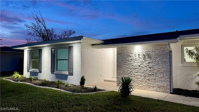 property exterior at dusk with a lawn