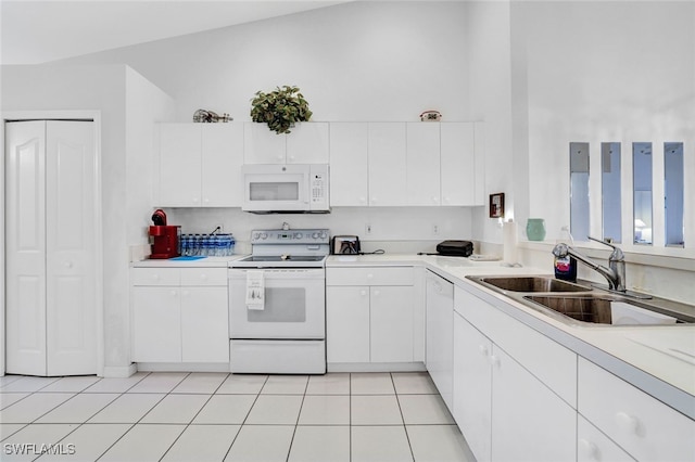 kitchen featuring light tile patterned flooring, a towering ceiling, sink, white cabinets, and white appliances