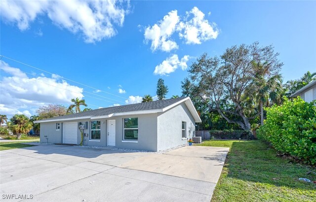 ranch-style house with a front yard, central AC unit, and a garage