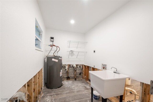 laundry area with electric dryer hookup, electric water heater, wood-type flooring, hookup for a washing machine, and sink