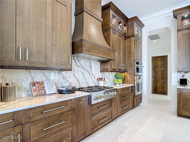 kitchen featuring custom exhaust hood, tasteful backsplash, light stone counters, and stainless steel appliances