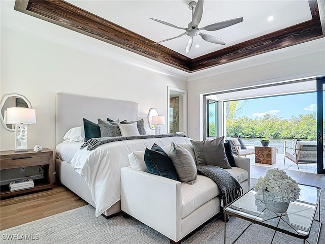 bedroom with ceiling fan, ornamental molding, access to outside, a raised ceiling, and light wood-type flooring