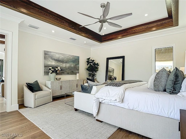 bedroom featuring hardwood / wood-style flooring, ceiling fan, crown molding, and a raised ceiling