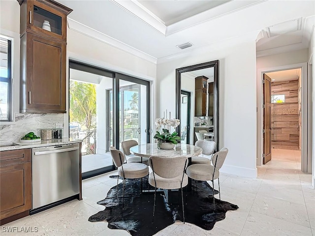 dining room with a raised ceiling, crown molding, and sink