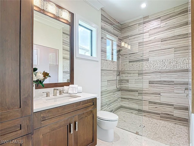 bathroom featuring vanity, a tile shower, and toilet