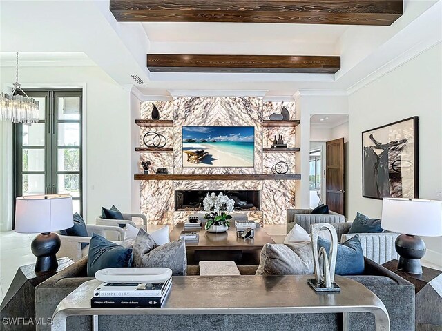 living room with crown molding, a stone fireplace, and a chandelier