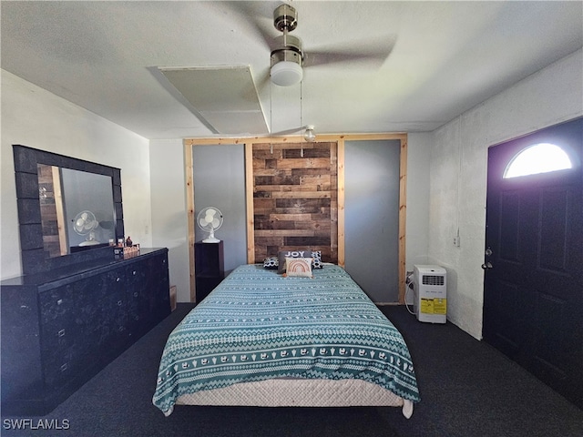 carpeted bedroom featuring ceiling fan and wood walls