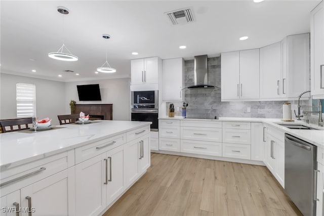 kitchen with wall chimney range hood, stainless steel appliances, sink, white cabinets, and light hardwood / wood-style floors