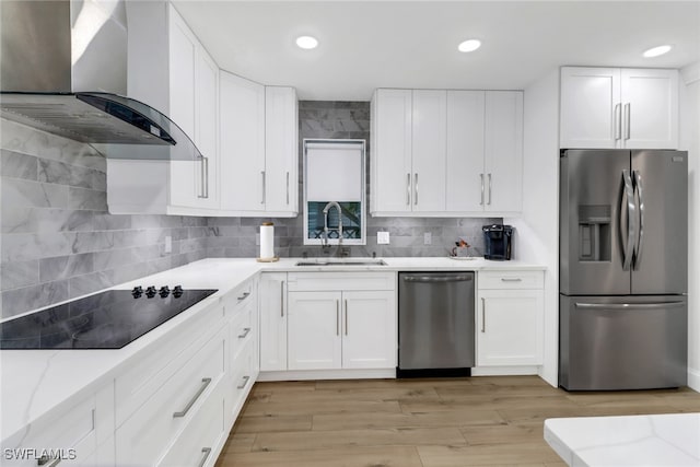 kitchen with wall chimney range hood, light hardwood / wood-style flooring, stainless steel appliances, and sink