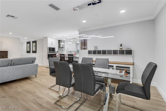 dining space featuring ornamental molding and light wood-type flooring