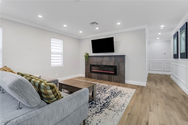 living room with light hardwood / wood-style floors, crown molding, and a fireplace