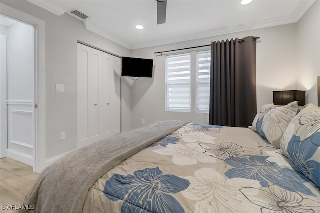 bedroom featuring light hardwood / wood-style floors, a closet, ornamental molding, and ceiling fan