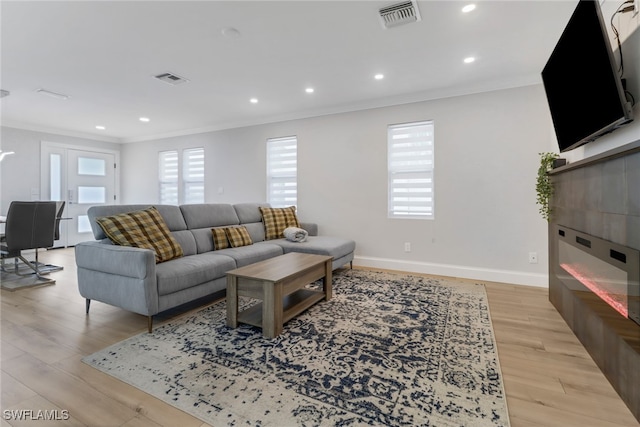 living room with crown molding and light wood-type flooring