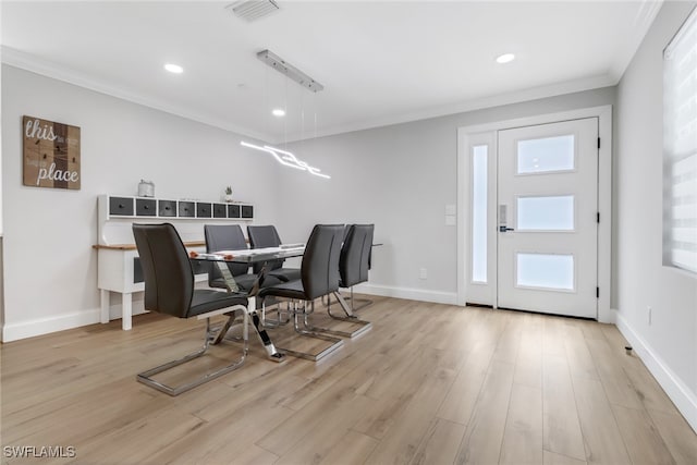 dining space featuring crown molding and light wood-type flooring