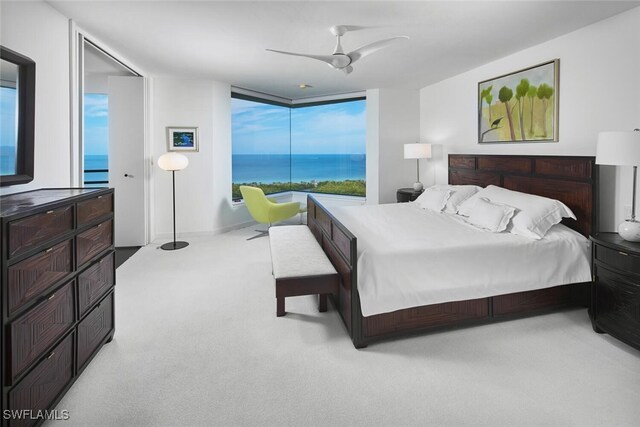 bedroom featuring ceiling fan, a water view, and light carpet