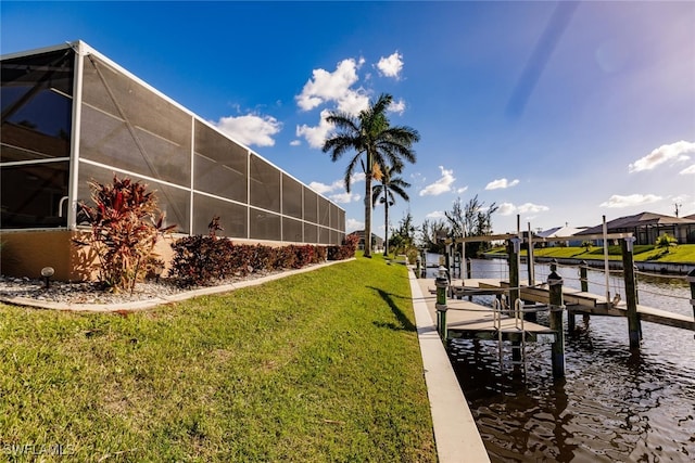 dock area with a water view, a lanai, and a lawn