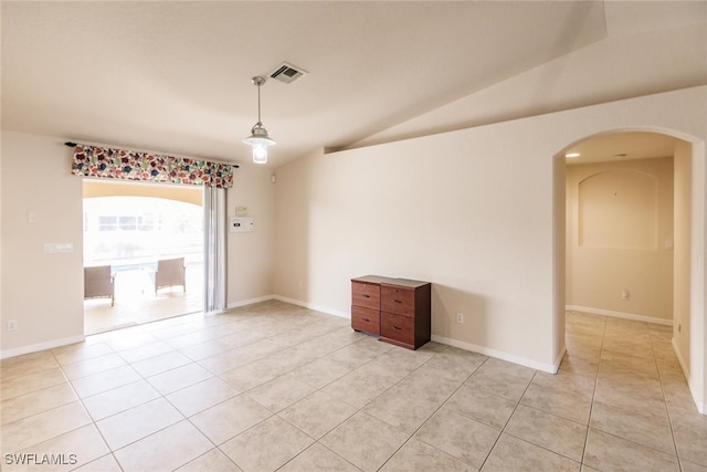 tiled spare room featuring lofted ceiling