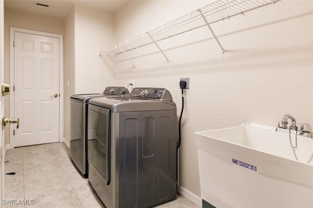 washroom featuring sink, washing machine and clothes dryer, and light tile patterned floors