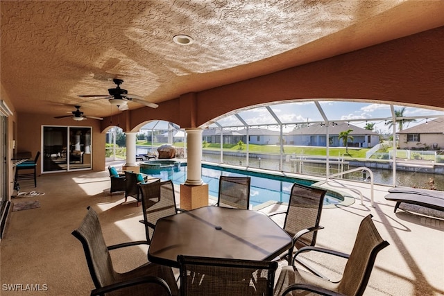 view of patio / terrace with ceiling fan, a water view, and a lanai