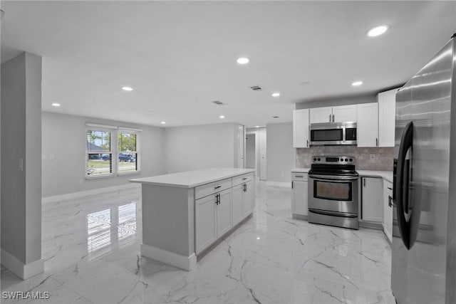 kitchen with white cabinets, appliances with stainless steel finishes, decorative backsplash, and a kitchen island