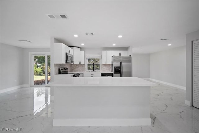 kitchen with a center island, white cabinets, sink, decorative backsplash, and appliances with stainless steel finishes