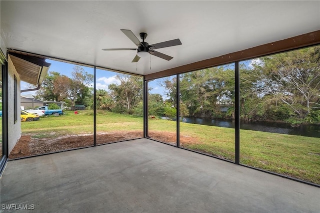 unfurnished sunroom with ceiling fan and a water view