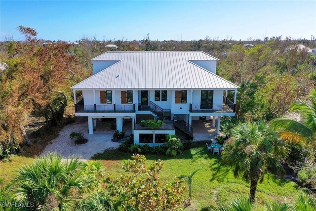 back of property with metal roof, a yard, stairway, and a wooded view