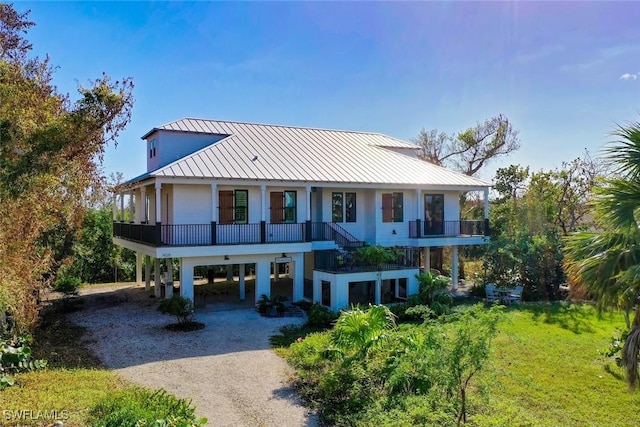 coastal inspired home with a carport, covered porch, metal roof, and dirt driveway