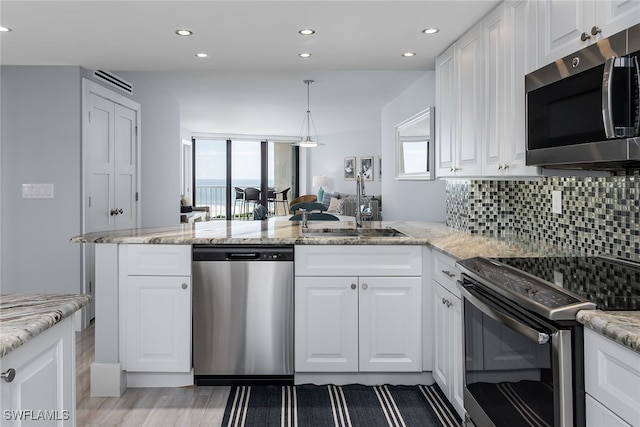 kitchen with kitchen peninsula, white cabinets, tasteful backsplash, hardwood / wood-style floors, and appliances with stainless steel finishes