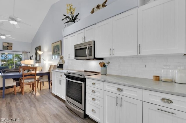 kitchen featuring decorative backsplash, white cabinets, ceiling fan, light hardwood / wood-style flooring, and stainless steel appliances