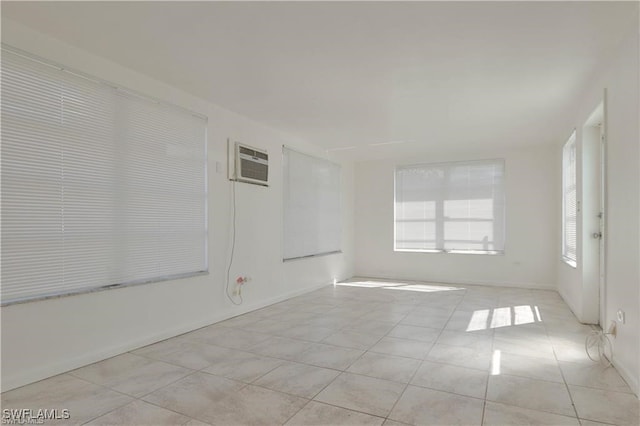 spare room featuring an AC wall unit and light tile patterned floors