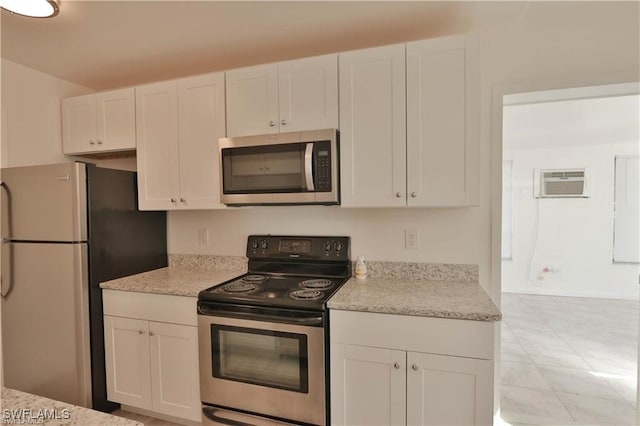 kitchen featuring white cabinetry, a wall mounted AC, appliances with stainless steel finishes, and light stone counters