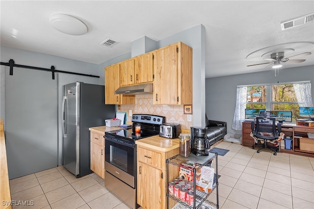 kitchen with decorative backsplash, stainless steel appliances, a barn door, light tile patterned flooring, and ceiling fan