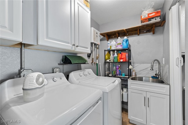 laundry area with sink, a textured ceiling, separate washer and dryer, and cabinets