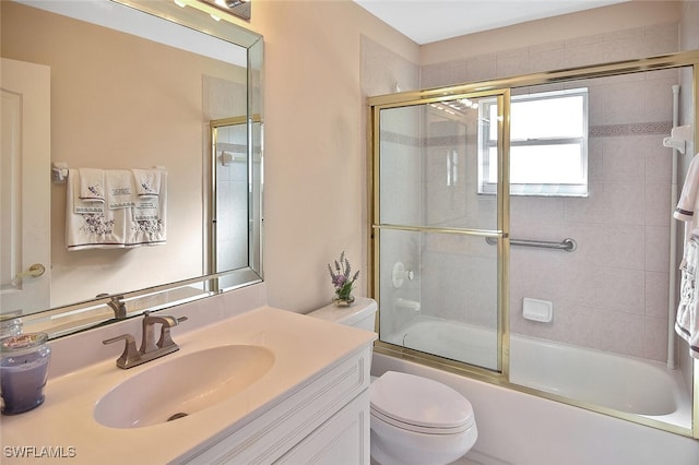 full bathroom featuring vanity, combined bath / shower with glass door, and toilet