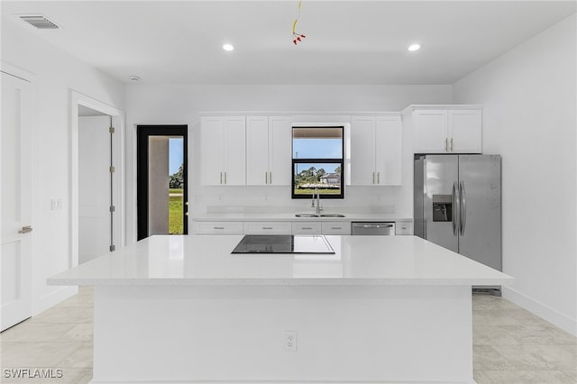 kitchen with sink, a kitchen island, appliances with stainless steel finishes, and white cabinets