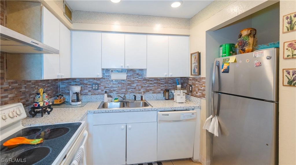 kitchen featuring white appliances, backsplash, white cabinets, wall chimney range hood, and sink