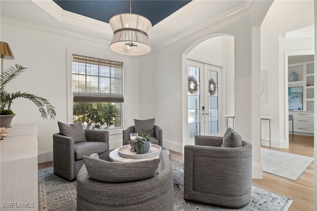 living room featuring french doors, crown molding, wood-type flooring, and a raised ceiling