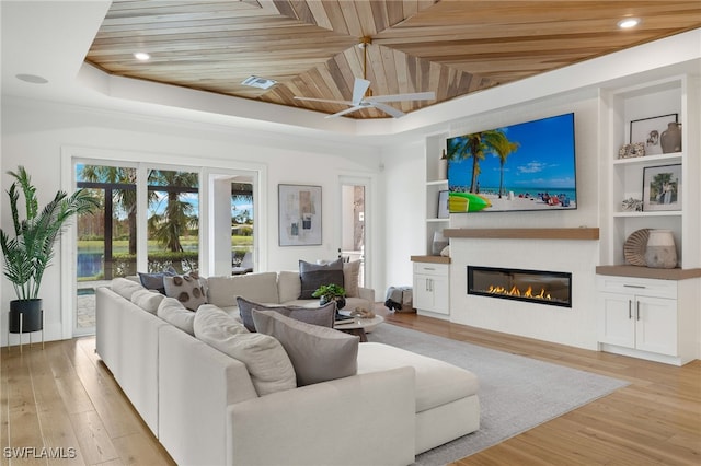 living room with built in features, wood ceiling, a tray ceiling, and light wood-type flooring