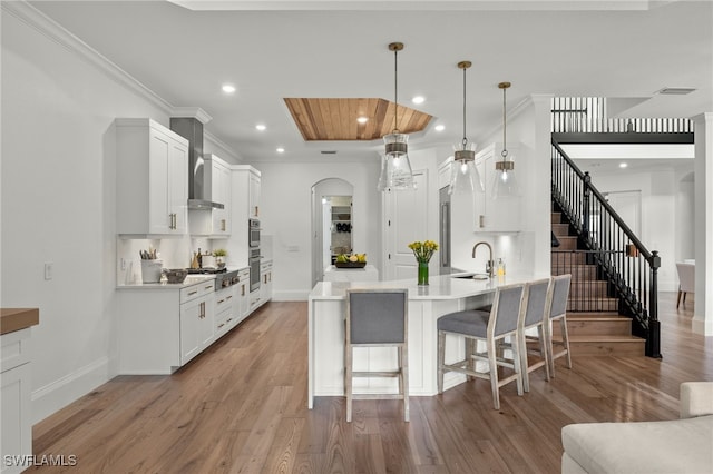 kitchen with white cabinetry, light hardwood / wood-style flooring, decorative light fixtures, and sink