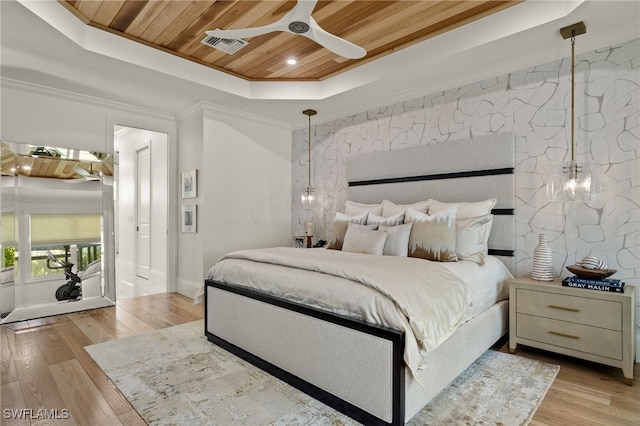 bedroom featuring wood ceiling, a raised ceiling, light hardwood / wood-style floors, ceiling fan, and crown molding