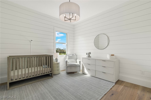 unfurnished bedroom featuring wood walls, wood-type flooring, and a nursery area