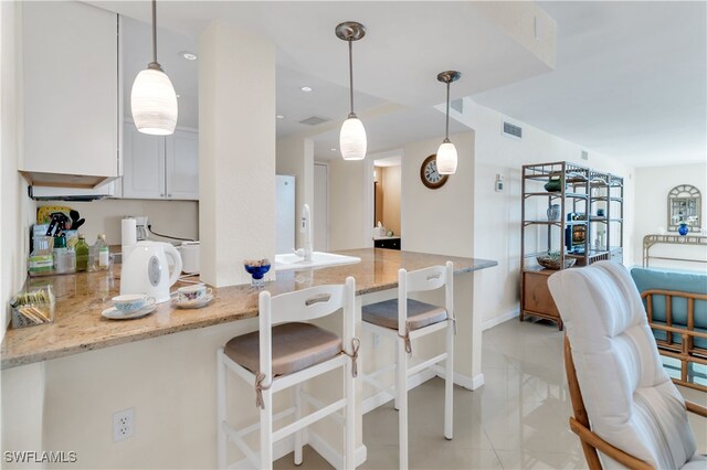 kitchen with white cabinetry, decorative light fixtures, and light stone counters