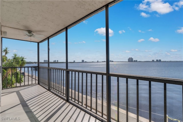 unfurnished sunroom with a water view and ceiling fan