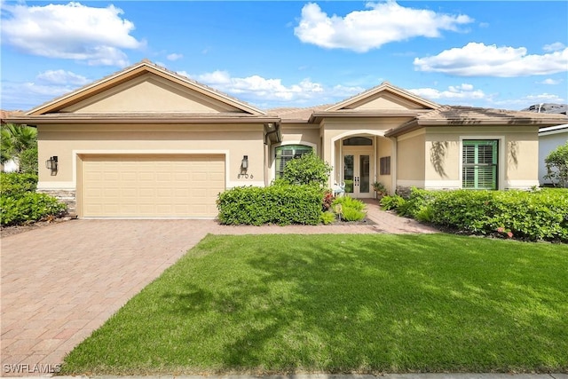 ranch-style home with a front lawn, french doors, and a garage